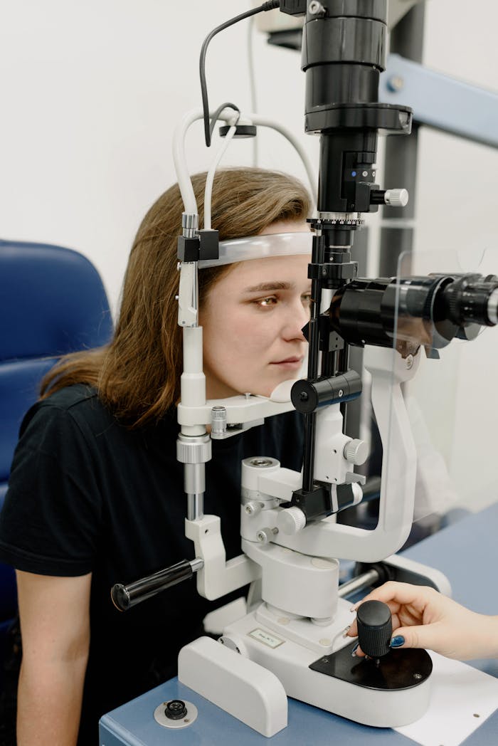 A young woman receives an eye examination using modern ophthalmology equipment in a clinic setting.