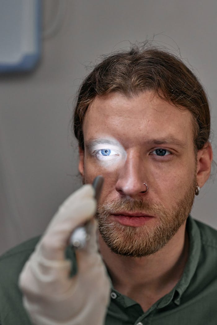 A man undergoes an eye examination in a clinical setting with a focused light.