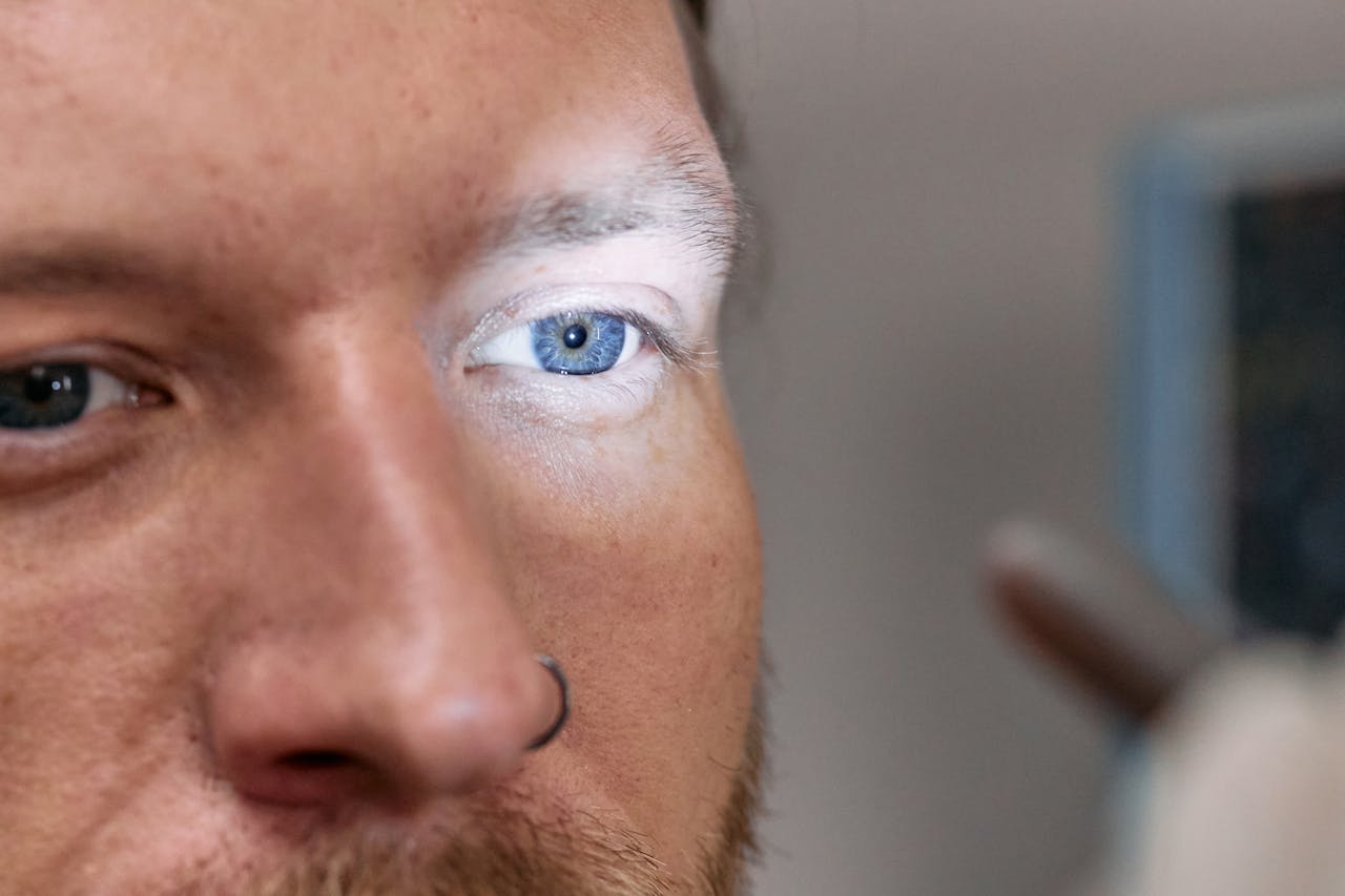 A close-up view of a man's blue eye under examination light by an ophthalmologist.